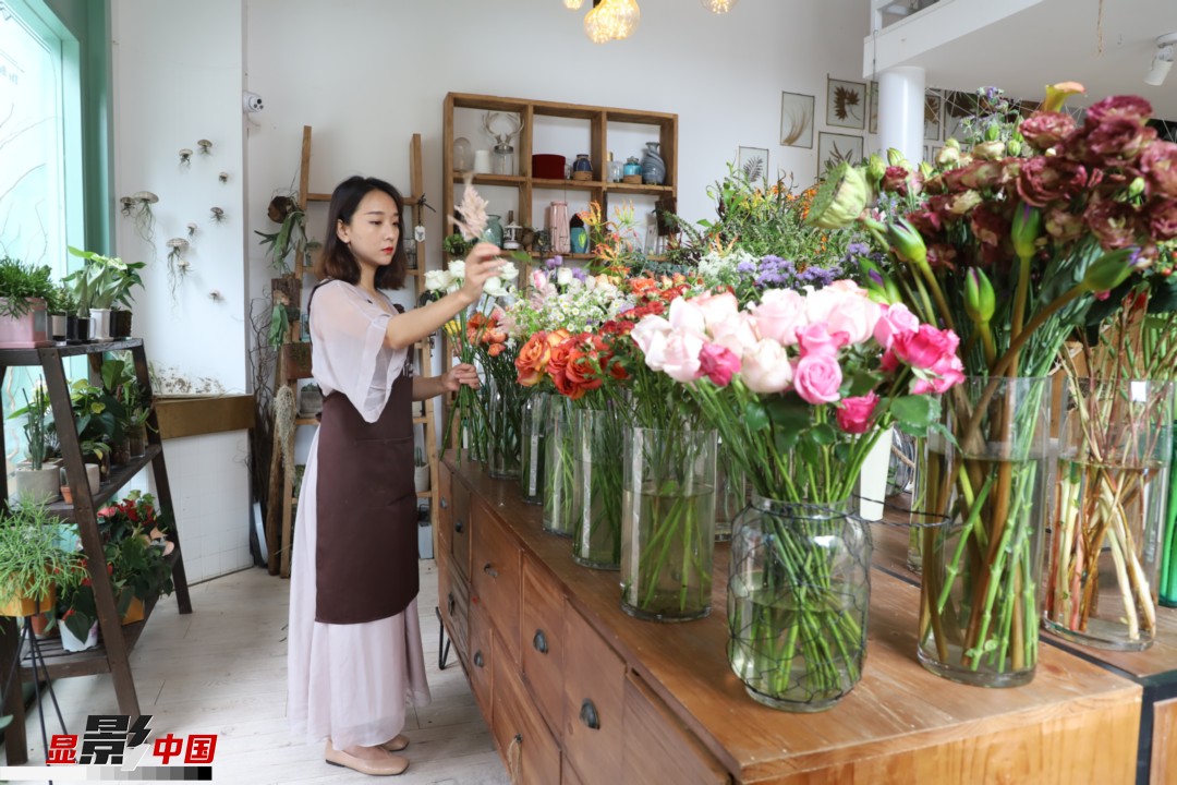 王黎媛是一名河南姑娘，在昆明念完大學(xué)后，就再也舍不下春城的藍(lán)天陽光、青山碧水，更舍不下這里的四時繁花，于是就干脆留了下來，成了一名媒體人。2017年的時候又毅然辭去工作，創(chuàng)業(yè)開起了花店，成了都市里的一名“花房姑娘”。圖為王黎媛在自己的花店中整理鮮花。新華網(wǎng) 周亞平/攝 念新洪/文